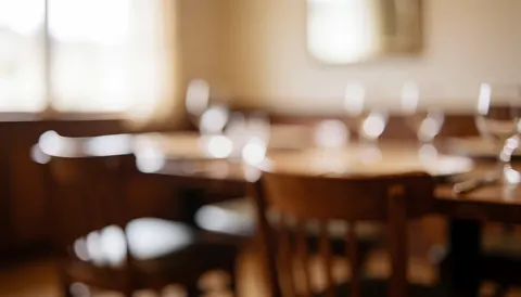 Warm blurred dining room background featuring wooden tables and chairs, suitable for bed and breakfast text overlays