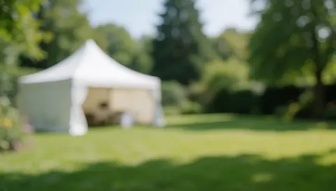 White canopy tent in a garden with green grass and trees, ideal for outdoor events and business text backgrounds.