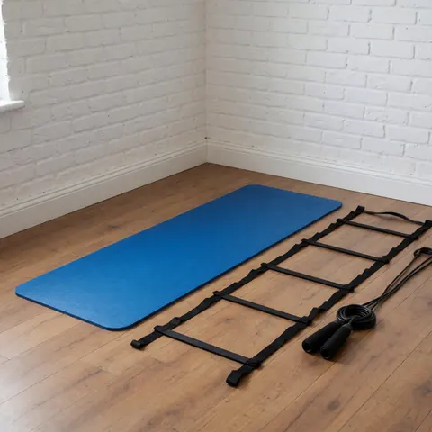 Blue exercise mat, black agility ladder, and jump rope on wooden floor with white brick walls for volleyball training