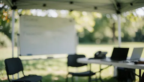 Whiteboard, chairs, and laptops on a table under a canopy, ideal for soccer coach text background