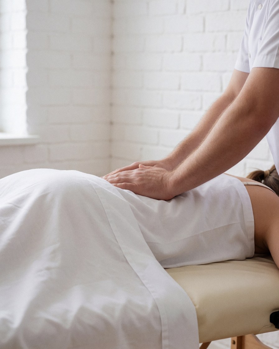 Masseuse applying pressure to a client's back during a therapeutic session