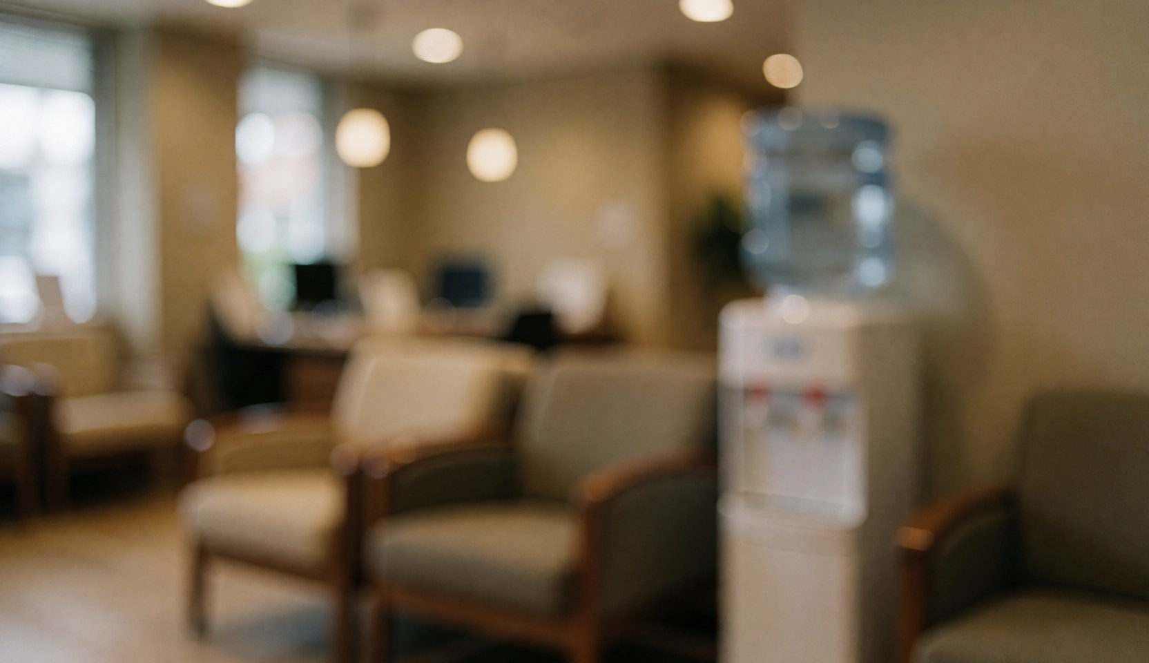 A waiting room background featuring wooden and fabric chairs, a water dispenser, and warm ambient lighting for professional care services.