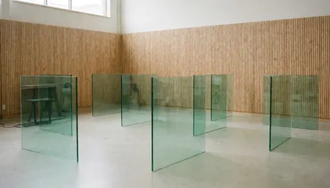 Standing tempered glass panels in a workshop with wooden walls and concrete floor, illuminated by natural light, ideal for a window repair business.