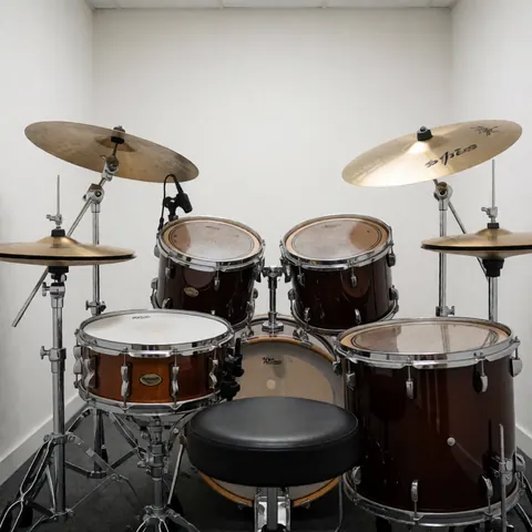 Complete acoustic drum set with cymbals and stool in a music academy practice room with white walls and bright lighting