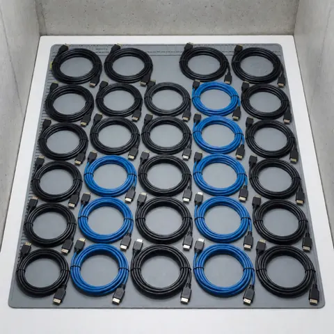 Rows of HDMI and LVDS cables organized on an anti-static mat for television repair, set against a concrete background.