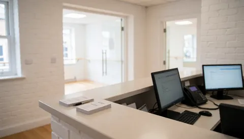 Reception area of a dance studio featuring desks, computers, class cards, and an entrance to practice rooms