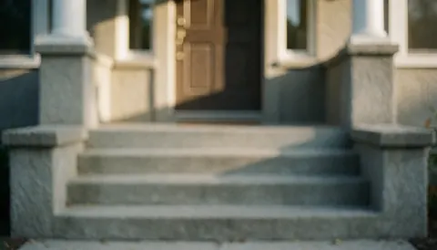 Concrete staircase leading to an entrance door with warm sunset light, suitable as a background for staircase repair services