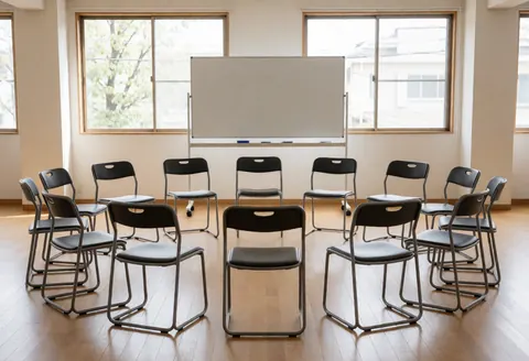 A writing room with chairs in a circle, a whiteboard, and large windows, ideal for group sessions and creative workshops.