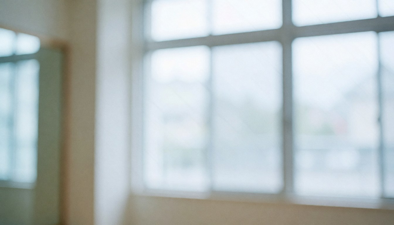 Empty dance studio interior featuring large windows, a mirror frame, soft cool lighting, and white walls, providing a clean background for text overlays.