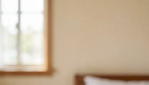 Warm bedroom wall background featuring a window frame and bed headboard with soft lighting and warm tones suitable for text overlay