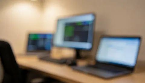 A diagnostic workspace featuring a desk with blurred computer monitors and a laptop, suitable as a background for computer repair services.