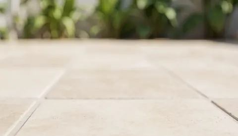 Beige tiled pool surface with out-of-focus green foliage and natural light, suitable for business text overlays