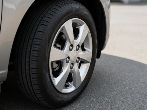 Close-up of a new tire with alloy rims mounted on a compact vehicle parked on asphalt, suitable for car sales marketing.
