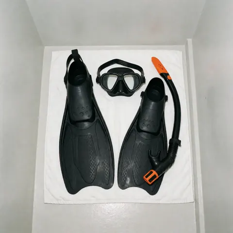 Black swim fins and orange snorkel with diving mask arranged neatly on a clean white towel, swimming coaching equipment for product display