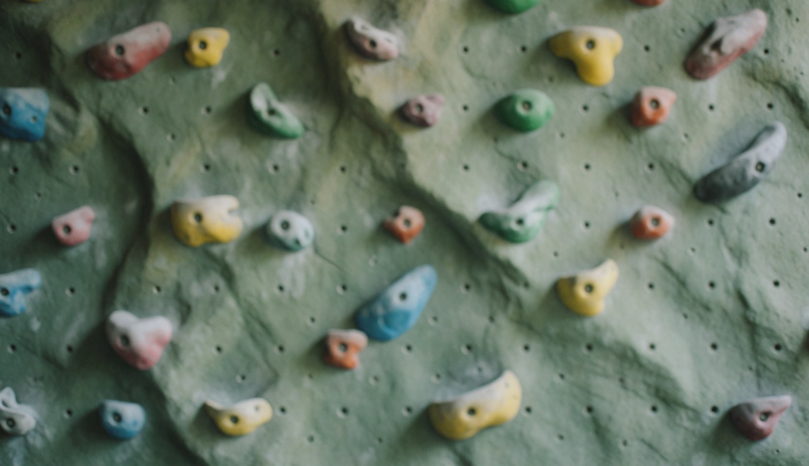 Artificial climbing wall with colorful handholds and rock texture, ideal background for adventure park text.