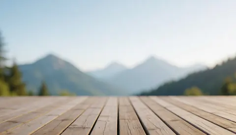 A wooden terrace deck with blurred mountains in the background, ideal for text overlays or mountain shelter advertisements