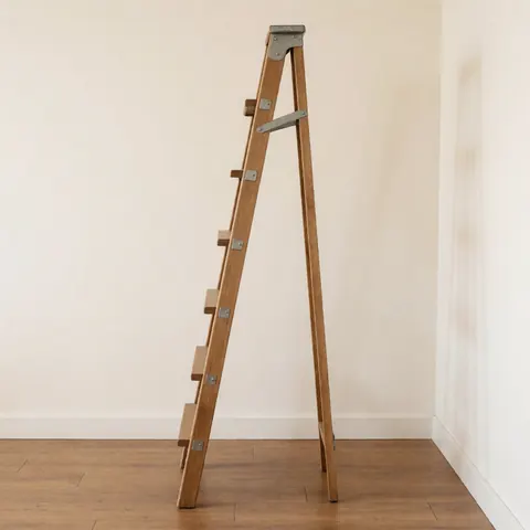 Wooden ladder with steps used for vertical display, ideal for interior decoration with wooden floors and white walls.