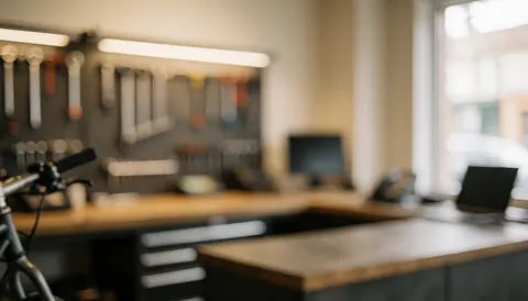 Neat and well-lit bicycle workshop background featuring hanging tools on a work surface.