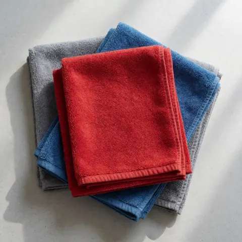 Red blue and gray microfiber towels neatly arranged on concrete surface for vehicle cleaning