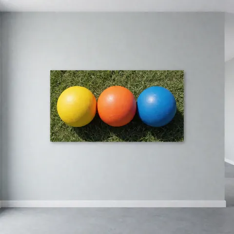 Three yellow, orange, and blue training soccer balls resting on green grass, ideal for soccer coaches.