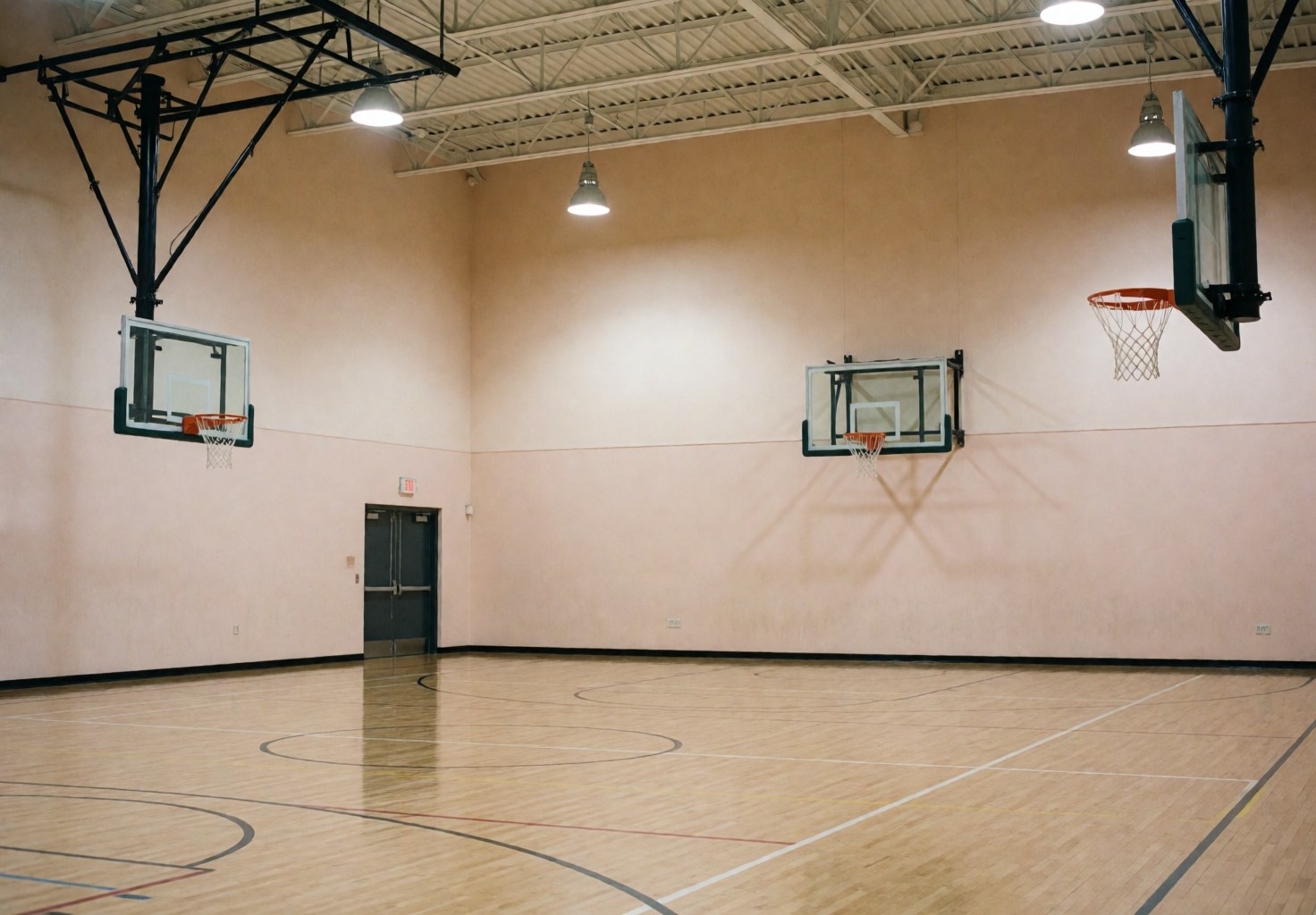 Empty basketball gymnasium featuring polished wooden flooring, beige walls, and hoops ready for play, suitable for sports facility installers.