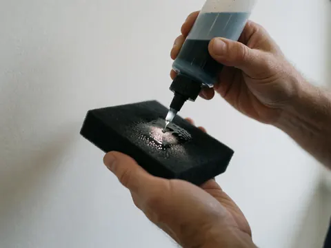 Close-up of ceramic coating droplets on a black cloth for automotive paint detailing