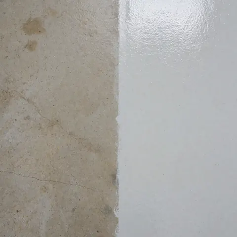 Close-up view of an industrial concrete wall showing a clear contrast between a dirty section and a thoroughly cleaned area after professional cleaning.