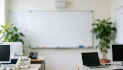 Whiteboard, green plants, and computers on tables in a Spanish classroom setting, ideal for text overlays.