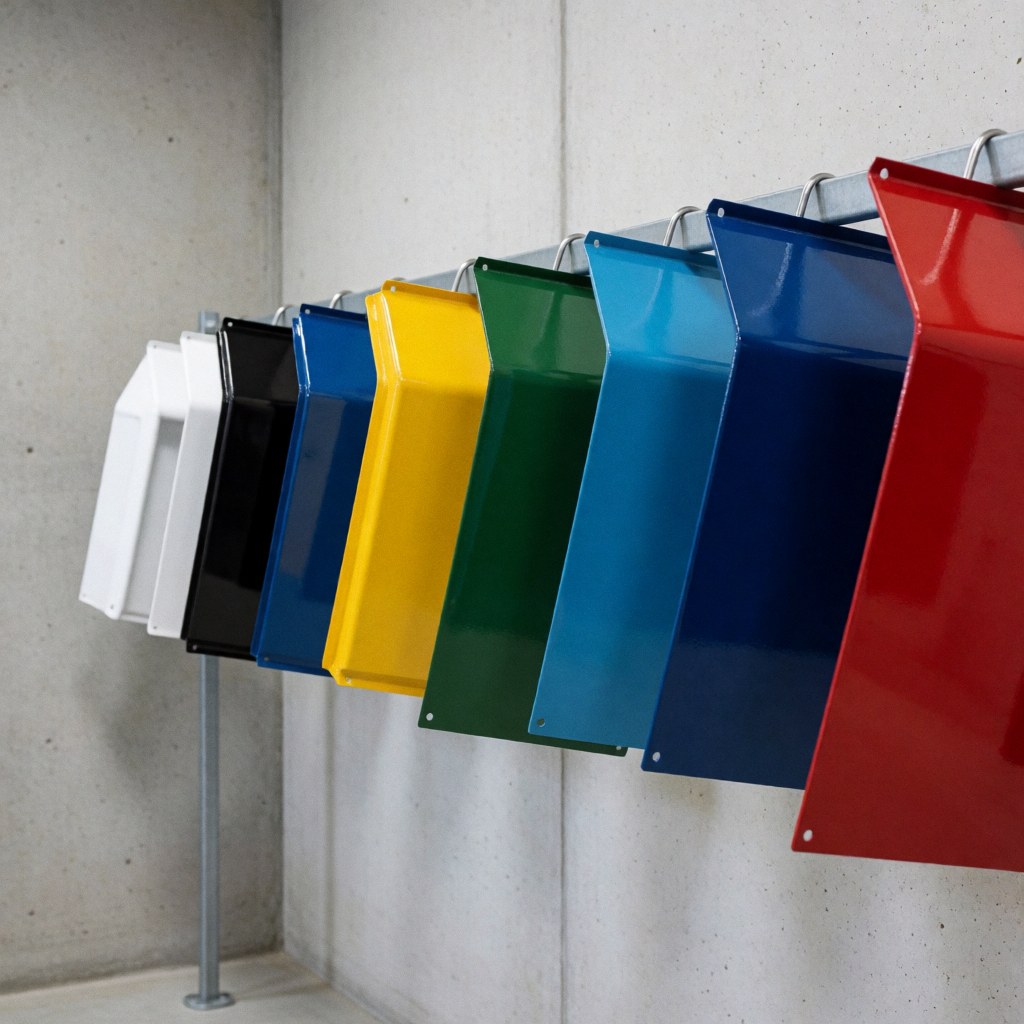 Freshly painted metals in vivid colors hanging on a metal shelf against polished concrete walls with a refined industrial finish