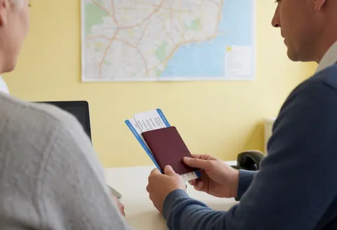 Professional reviewing travel documents with a client in an office setting, illustrating insurance or travel services
