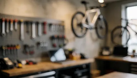 Hanging bicycles in a bike workshop with tools on racks, warm lighting, and neutral walls