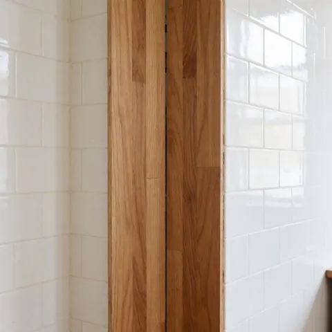 Close-up detail of polished wood flooring with seamless joints set against glossy white ceramic tile walls, highlighting craftsmanship for flooring installation businesses.