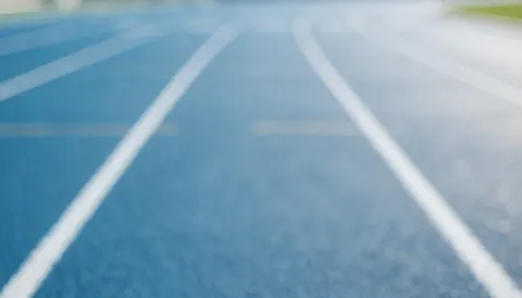 Out-of-focus blue running track with white lane lines, serving as a clean background for text overlays.