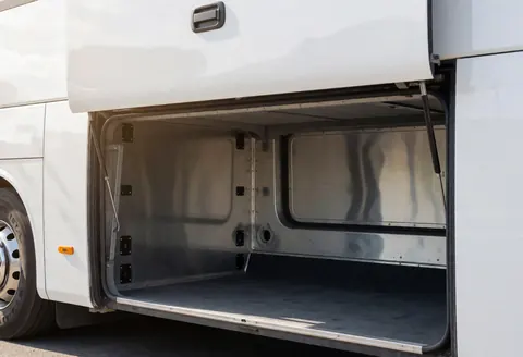 Empty and clean tour bus luggage compartment with visible metal walls and tie-down points, ideal for storing luggage.