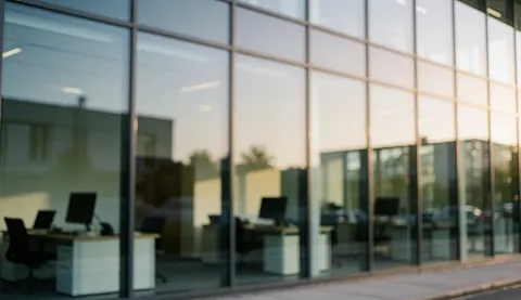 Modern office interior featuring reflective glass windows and warm sunset lighting, suitable for business text overlays