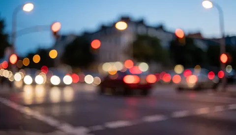 Blurry urban background with traffic lights, streetlamps, and evening sky, ideal for freight transport text overlays