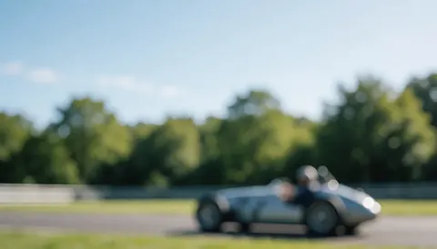 Background of a vintage race car on a track with green trees and blue sky, ideal for business text overlays