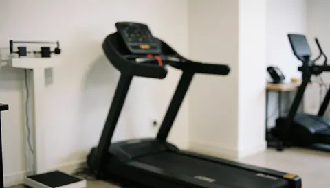 A treadmill and scale in a clean gym setting, ideal for text backgrounds with a professional atmosphere