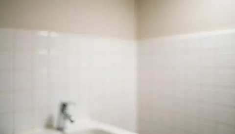 White tiled wall with a chrome faucet and soft lighting, serving as a clean background for commercial text overlays