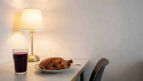 Plate of roasted chicken and purple corn beverage on a table with a lamp and white wall, suitable for restaurant use