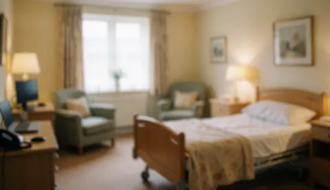A hospital bed in a senior care room with chairs, tables, and warm lighting, ideal for text background.