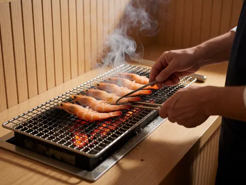 Close-up of shrimp cooking on a charcoal grill with visible smoke and texture in a wooden cevicheria kitchen