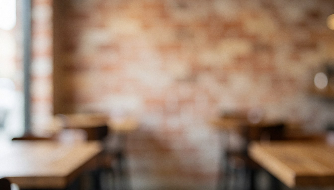 Warm blurred pizzeria interior featuring a brick wall and wooden tables, serving as an ideal background for text overlays.