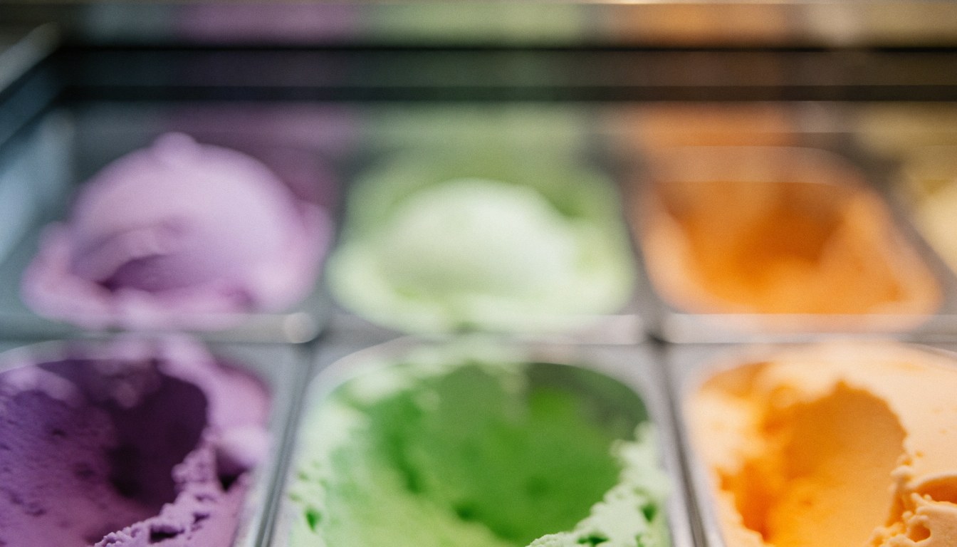 Colorful ice cream cones in a display case with a soft bokeh background and warm lighting suitable for text overlay