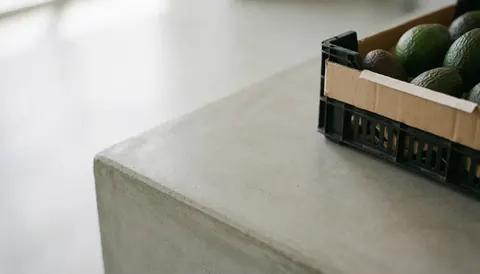 A box of avocados placed on a concrete surface with soft lighting, suitable as a text background for a grocery store.