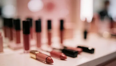 Soft pink and warm light blurred background featuring out-of-focus lipsticks, ideal for text overlay in beauty and perfumery contexts