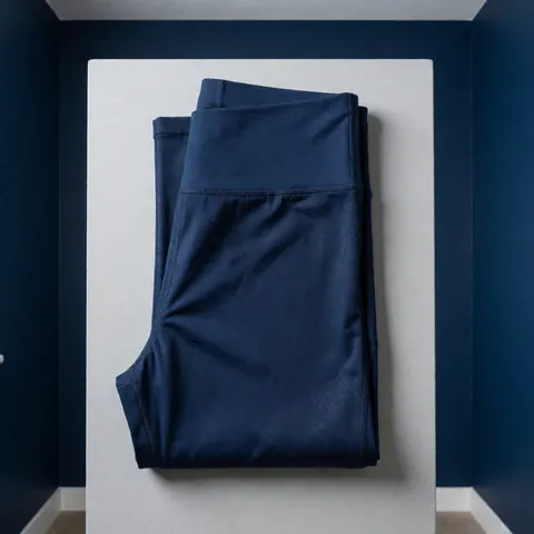 Folded navy blue textured sport leggings on a light gray surface with blue walls, product for sale