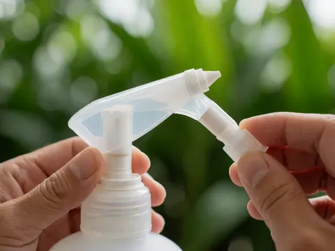 Close-up of a hygiene bottle nozzle at a diving school with water droplets and tropical foliage background