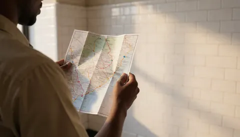 Tour guide holding a route map in a historic plaza with white tiled walls and morning light