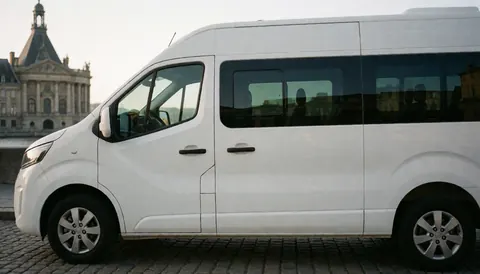 White van parked on cobblestone street in front of historic building for tour operator website